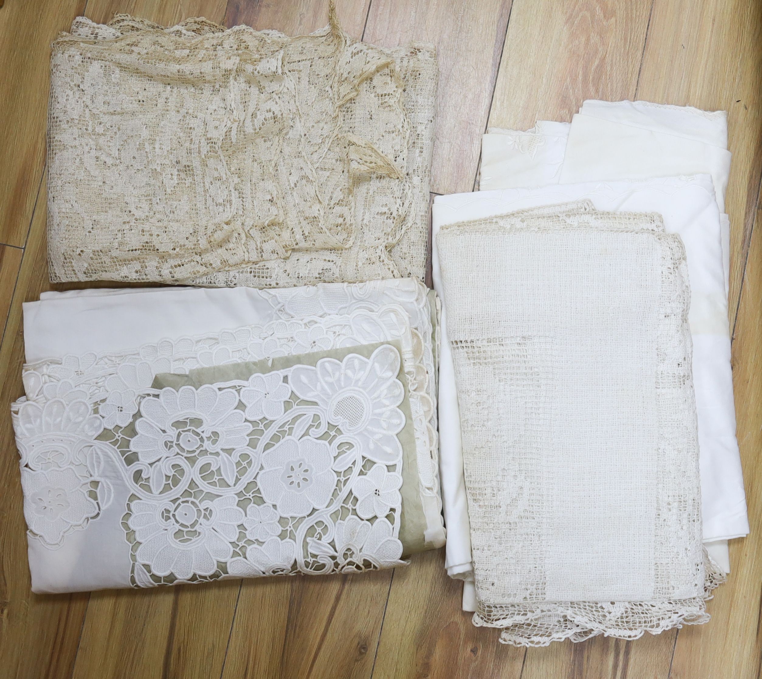 A collection of crochet edged linen tablecloths, a filet cloth and a 225cm long ornately cutworked cloth.